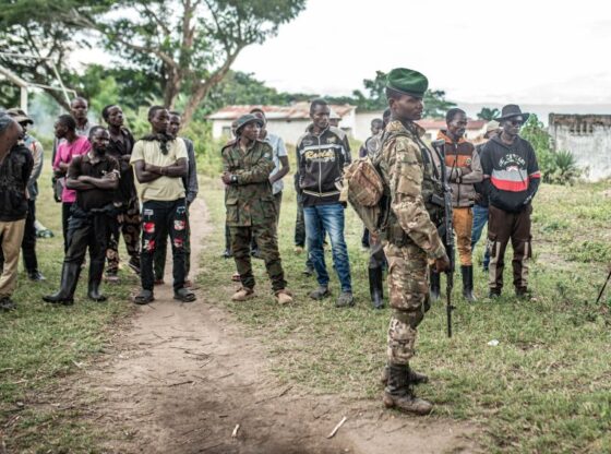 UVIRA, DEMOCRATIC REPUBLIC OF CONGO - DECEMBER 15: An M23 fighter looks on as Wazalendo militants surrender weapons to the Rwanda-backed M23 rebel group on December 15, 2025 in Uvira, Democratic Republic of Congo. Fifty-two members from the coalition of Congolese and Burundian militias known as the Wazalendo joined M23 following the rebels' capture of the South Kivu city on December 10. Human Rights Watch has reported abuses perpetrated against civilians by fighters from both sides of the conflict during the offensive on Uvira, and has called for the safe passage and humanitarian assistance for those caught up in the fighting. (Photo by Daniel Buuma/Getty Images)